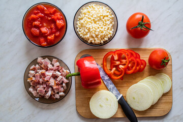 Home made food concept: top view on cutting board and food like tomatoes, red peppers, bacon and cheese