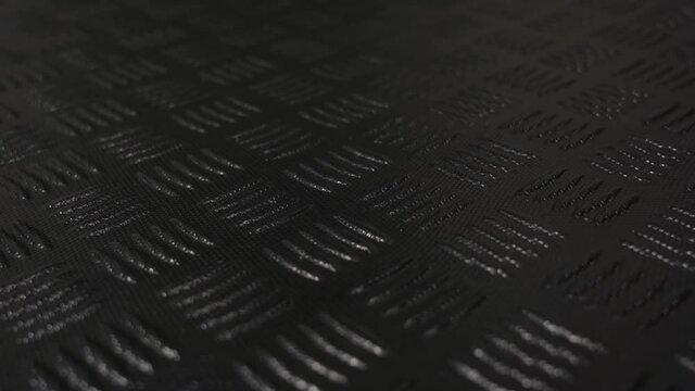 Closeup view 4k stock video footage of texture of black protective hdpe rug or mat for boot of automobile