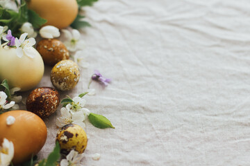 Fototapeta na wymiar Happy Easter! Easter eggs with spring flowers on rustic linen, space for text. Aesthetic holiday