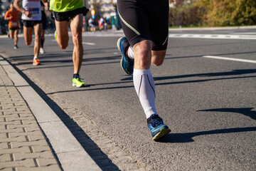 Legs of running marathon participants. Group of runners on city road.
