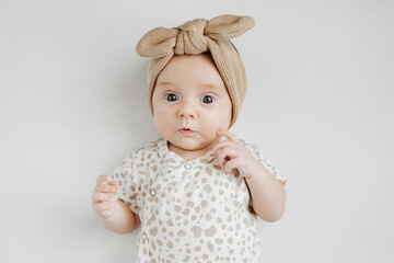 Portrait of baby girl in stylish headband. Cute infant on gray background. Fashion baby.