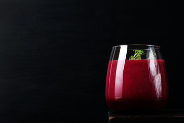 Smoothie with beet, berries and microgreen in the drinking glass against the black background. Copy space. Healthy nutrition