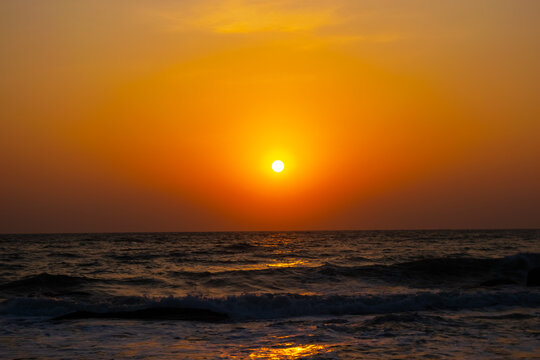 Colorful ocean beach sunrise with deep black and yellow sky and sun rays scenario image