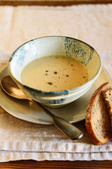 Cheese cream soup in bowl on beige linen table. Selective focus