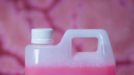 Bidón de plástico blanco con tapón de rosca blanco con lejía rosa sobre tela descolorida con lejía tye dye rosa - obrazy, fototapety, plakaty