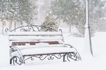 winter city park, benches covered in snow and snowfall