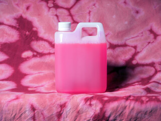 Bidón de plástico blanco con tapón de rosca blanco con lejía rosa sobre tela descolorida con lejía tye dye rosa - obrazy, fototapety, plakaty