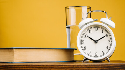 A mask, a glass of water, a book, pills, and an alarm clock. Restoring sleep patterns and treating insomnia