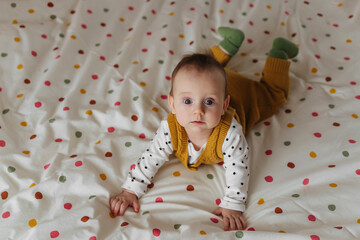 Baby in knitted stylish clothes    on bed at home. Fashion baby. Happy childhood.