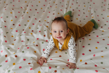 Baby in knitted stylish clothes  smiling  on bed at home. Fashion baby. Happy childhood.