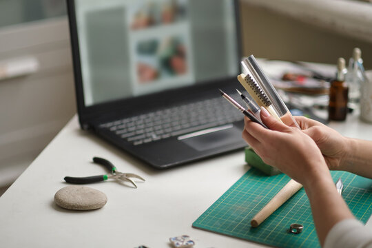 woman jeweler conducts online lesson in front of laptop. the teacher is taking online classes or watching a video tutorial on creating jewelry