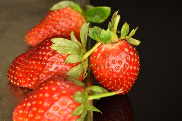 Several berries of bright red ripe organic delicious strawberries on a metal tray.