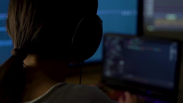 Software developer freelancer woman female work with program code C ++, Java, JavaScript on multiple displays on workplace at night. Programmer girl develops web desktop mobile application, framework.