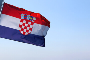 Flag of Croatia, blowing in the wind. Bright blue sky in the background.