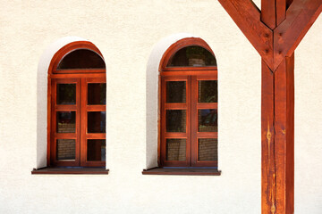 View of the arched windows of an old Ukrainian rural hut with a wooden support for the roof of the terrace.