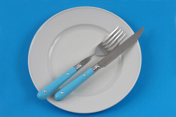 Assiette et couverts sur fond bleu