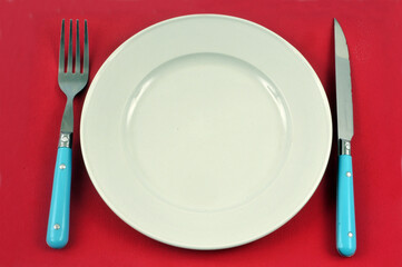 Assiette et couverts sur fond rouge