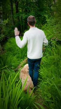 Hombre blanco joven con perro pidiendo stop en camino en bosque verde de asturias