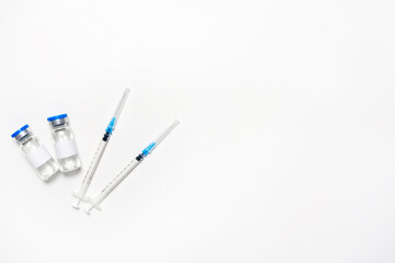 Flat lay of syringes and bottles for influenza vaccine on the white background. The concept of injection for prevention and health care. Vaccination. Top view, lay out, copy space, ampoule mockup.