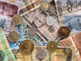 Group of money stack of banknotes from all over the world with some coins on top