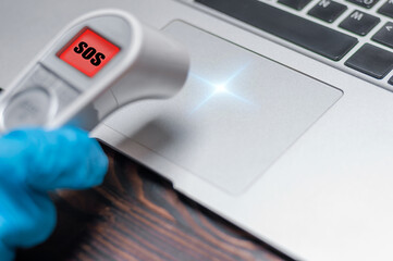 The technician applies an infrared thermometer to the laptop panel. Analysis of problems. Computer...