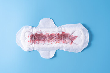 Used Sanitary pad, Sanitary napkin on blue background. Menstruation, Feminine hygiene, top view.