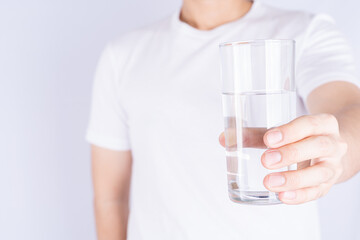 Man holding glass of water isolated grey background. Clean drinking water in clear glass.
