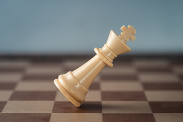 white chess king falling on chess board concept of failing.