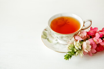 Porcelain cup of herbal tea and flowers on light background. Selective focus, soft focus. copy space