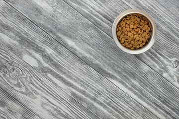 Food for cat in bowl on wooden backround. Top view. Copy space. Minimalism.