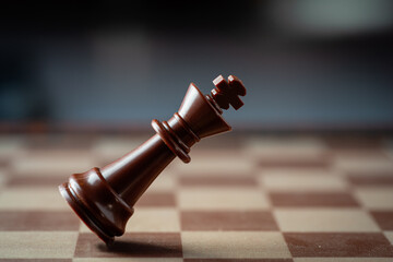 black chess king falling on chess board concept of failing.