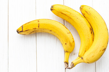 Ripe yellow bananas lie on a white table