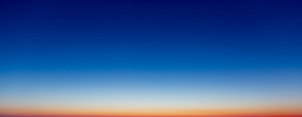 The sky before sunrise, dawn is over the sea, the stars are still visible in the dark sky, but a red dawn is already breaking over the horizon.