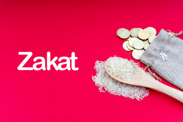 ZAKAT words with Coins and Rice on red background. Zakat concept. Zakat is a form of alm-giving as a religious obligation