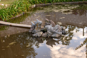 Obraz na płótnie Canvas statue of fish and rocks in a small pond