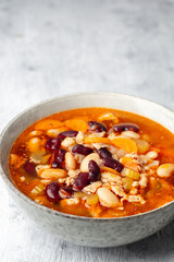 Bean soup with bacon, carrot, celery and onion in bowl on concrete background