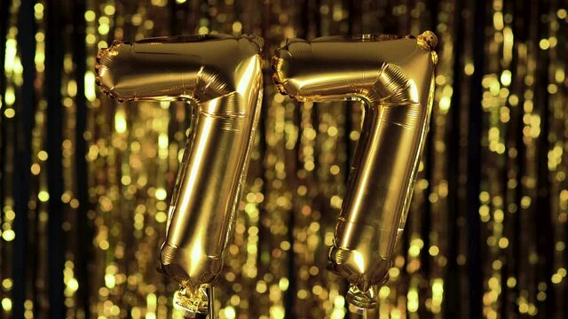 The golden number 77 seventy seven is made from an inflatable balloon on a yellow background. One of the complete set of numbers. Birthday, anniversary, date concept