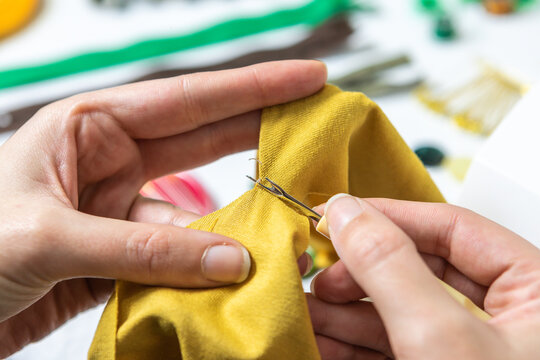 Removing stitches from a piece of clothing. Close-up of hands using a seam ripper and working with textile.