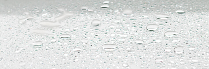 water drops on a glass surface, white color monochrome banner 