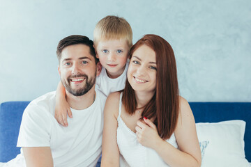 Fototapeta premium Young family woman, husband and son having fun together in a large bedroom in the morning