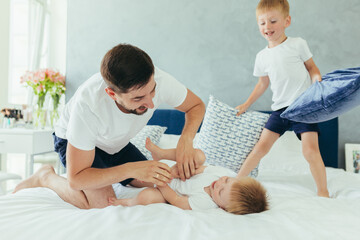 Fototapeta premium husband father playing with his children, two little boys brothers, in a large bedroom