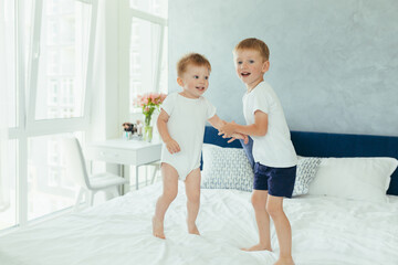 Two little boys brothers are playing in their parents' bedroom