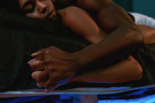 My love, my world. Young african sensual couple in love holding hands while sleeping together on the bed after having sex