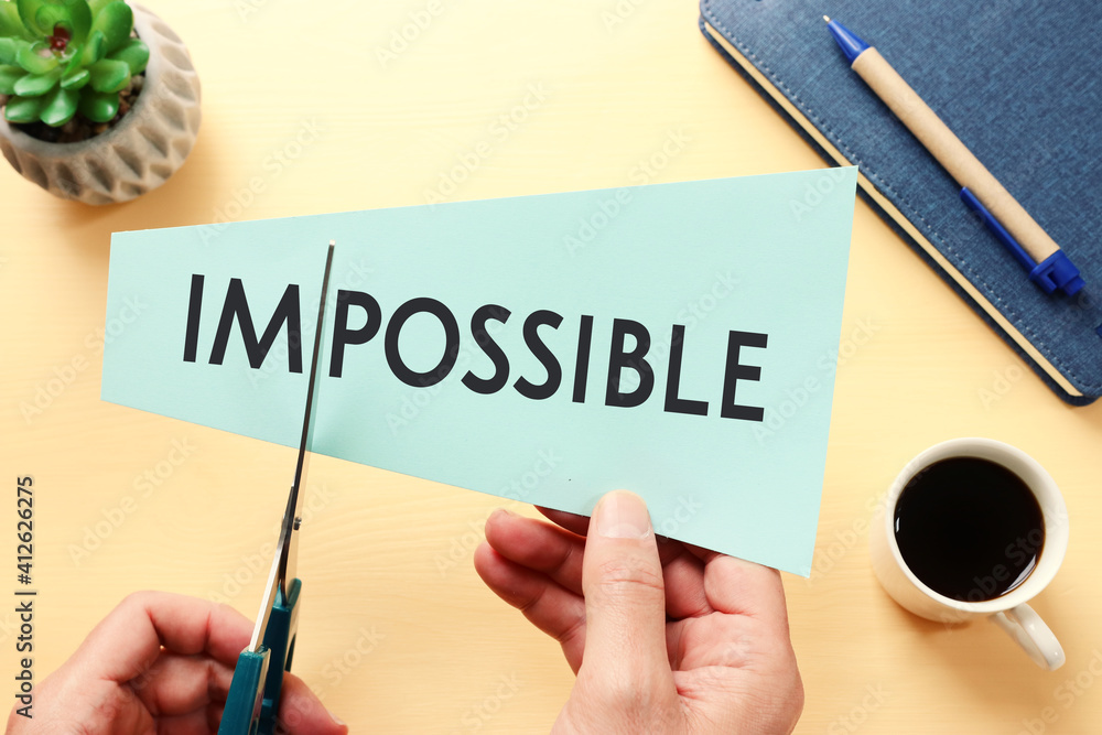 Poster man hand holding card with the text impossible, cutting the word im so it written possible. success 