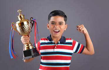 Indian school boy holding a golden trophy cup	
