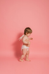 little girl in a diaper with angel wings on a pink background with space for text