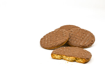 Broken chocolate covered biscuit against a plain white background, with whole biscuits. No people. Copy space.
