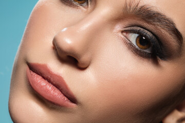 Celebrity. Close up of young female fashion model's face isolated on blue studio background. Beautiful caucasian woman with trendy make-up and well-kept skin. Style and beauty concept. Eyes.