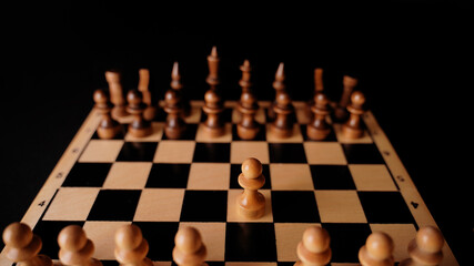 Close up of white and black chess pieces on board. Selective focus on first move of white pawn on chessboard. Concept of intelligent, logical and strategic game.