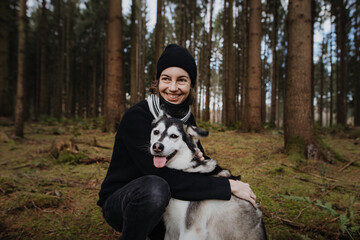 Junge Frau umarmt ihren Husky Mischling im Wald 